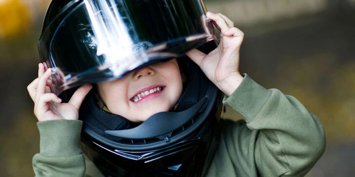 Ein Kind setzt einen Motorradhelm zum messen auf