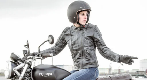 Eine Dame sitzt auf einer Triumph mit einem Motorradhelm für Damen