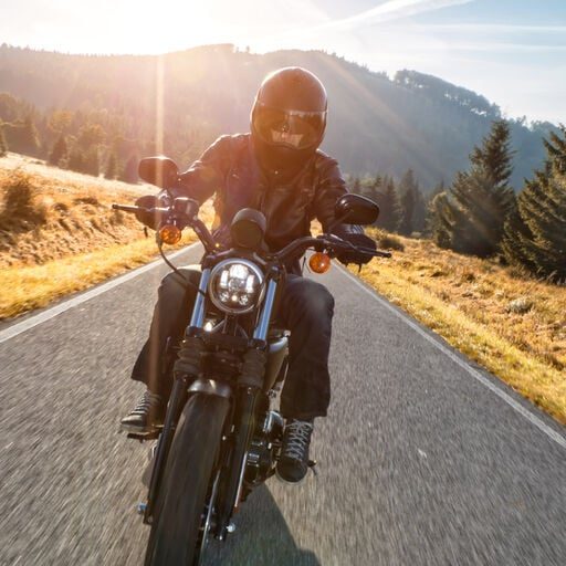 Ein Motorradfahrer trägt einen Helm mit Sonnenblende - eine gute Alternative zur Sonnenbrille unter dem Helm.