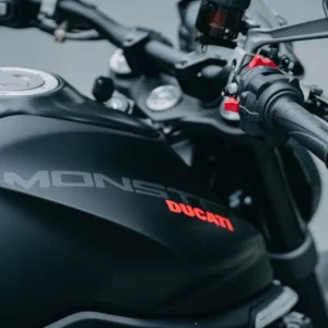 Detailaufnahme des Tanks und Lenkers einer Ducati Monster mit schwarzem Finish, rotem Ducati-Logo und Monster-Schriftzug.