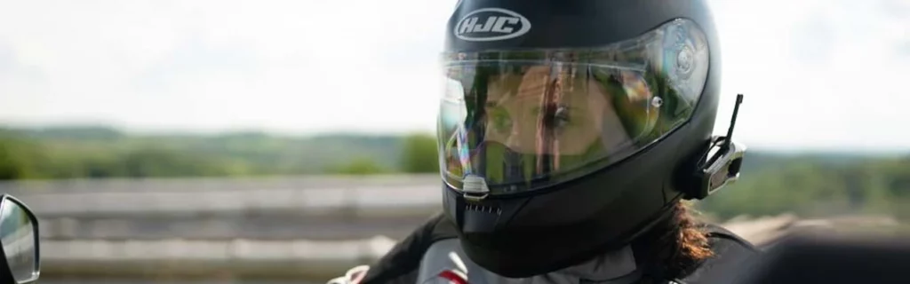 Frau mit Headset im Motorradhelm fährt Motorrad